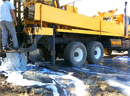 Yellow water well drilling rig truck pumping water during well installation in Northern California